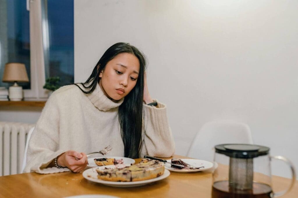 Woman staring at food with visible discomfort, symbolizing food anxiety and struggles with food control common in disordered eating.
