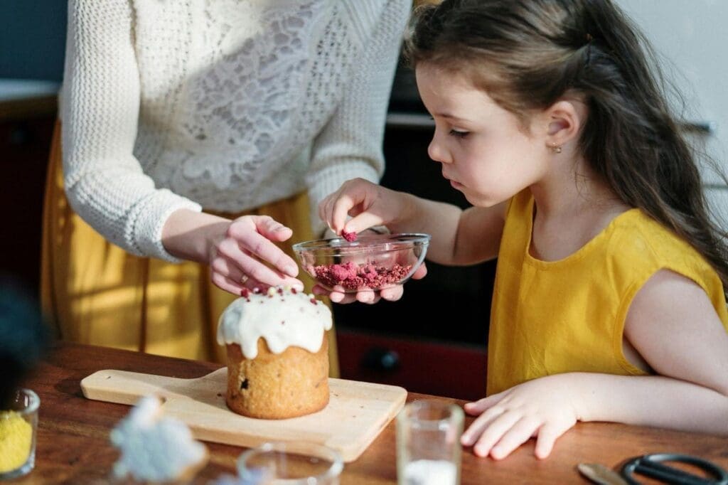 Parent and child decorating a cupcake together, showing a positive approach to picky eating and how to help a picky eater engage with food.