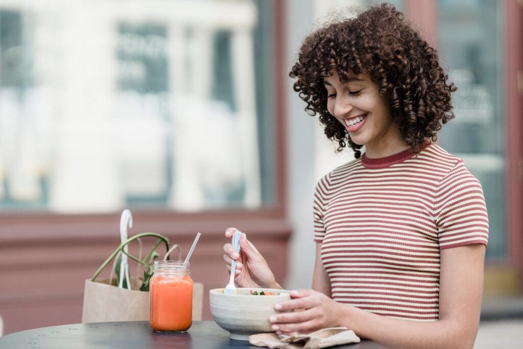 Woman smiling while enjoying a meal outdoors without counting calories