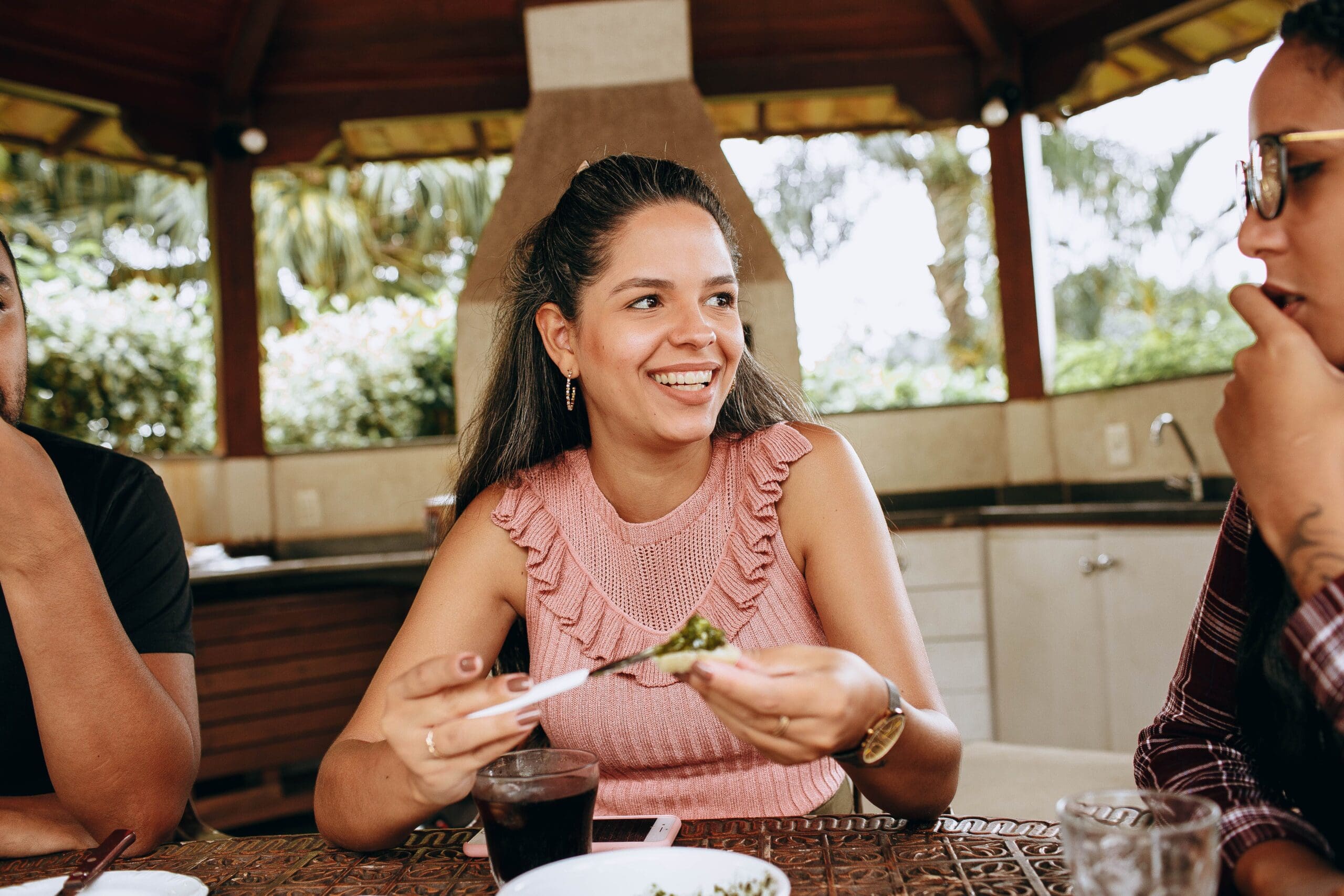 Woman enjoying a bite of food at an outdoor meal with friends, free from anxiety and food stress