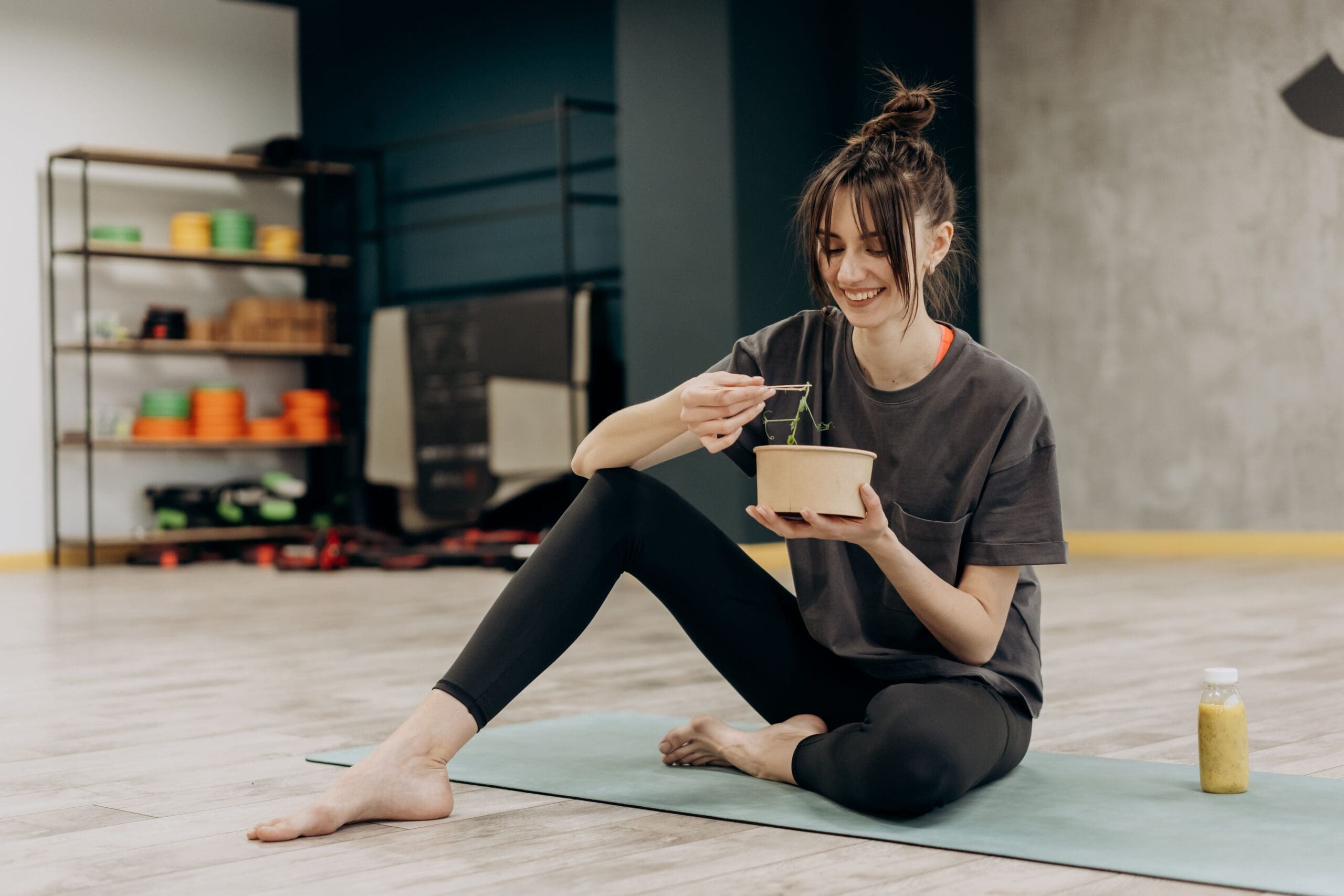 Woman in workout clothes eating a grain bowl after exercise